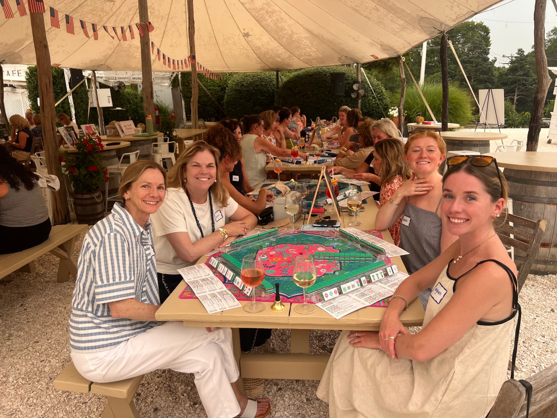 Players smiling around a Mahjong table at an outdoor Mahj with Sue event
